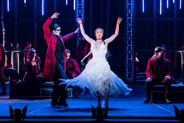 Aurora in her wedding dress is spun by Caradoc. The skirt of her dress swirls around her. Her arms are stretched above her.