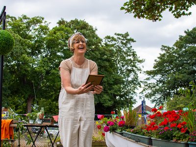 A female outdoor performer smiles holding a photograph
