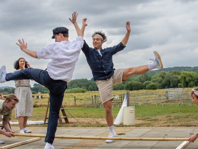 Two male dancers dance joyfully over moving poles
