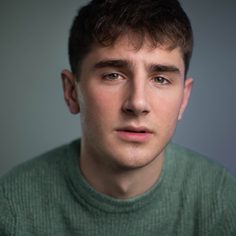 White male with brown hair wearing green jumper