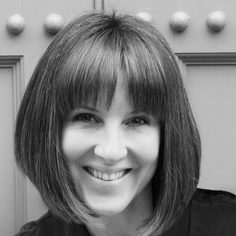 Woman with a short straight bob and full fringe smiles at the camera.