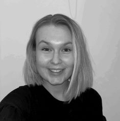 A White-British woman, in her late 20s, with straight, blonde shoulder length hair, beaming towards the camera.