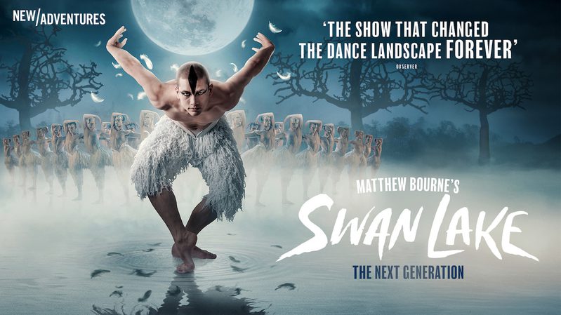 'The Swan' is bending forward with his knees bent and his arms behind him, he has black makeup on his face to resemble the features of a swan, and is wearing white feathered knee-length trousers. He is pictured standing in water and in a mist, his reflection is visible in the water. Feathers are falling from his arms, and behind him is a group of swans are posed with one arm curved over their head and the other stretched out to the side. There is a full moon above 'The Swan' and silhouettes of trees at the sides of the frame. The text reads "Matthew Bourne's Swan Lake The Next Generation". Above this is a quote which reads "'The show that changed the dance landscape forever'- Observer"