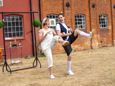 Two performers arm in arm, dance with teacups