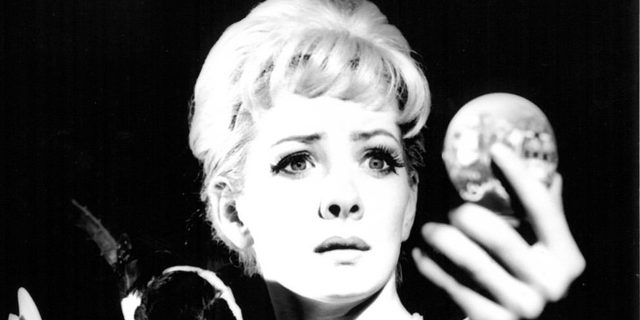 A 1992 black and white image of Ally Fitzpatrick looking into a pocket mirror in Deadly Serious